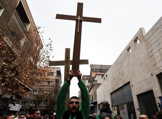 Der Mann, der an Heiligabend mit hoch erhobenen Armen ein Holzkreuz durch die Straßen von Damaskus trug, nachdem radikale Moslems in Sukailabija einen Weihnachtsbaum in Brand gesetzt hatten, ist ein wahrer Held des Jahres 2024.