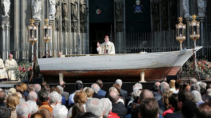 Nur ein Beispiel von vielen: Der Kölner Kardinal Woelki ließ 2016 zum Pontifikalamt an Fronleichnam ein Flüchtlingsboot als Altar vor dem Dom aufbauen.