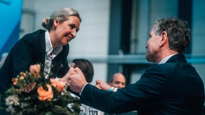 Der AfD-Parteitag in Riesa hat ein Symbolbild der Geschlossenheit erzeugt: Es zeigt Björn Höcke am Fuß der Rednerbühne und Alice Weidel, die sich zu ihm beugt, um Gratulation und Blumen entgegenzunehmen.